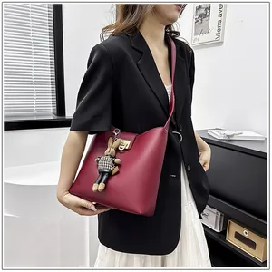 Détail du sac seau rouge foncé avec fermoir doré et breloque lapin sur le mannequin