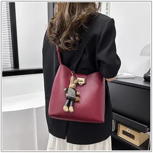 Détail du sac seau bordeaux avec charm lapin en peluche et fermoir en anneau doré élégant