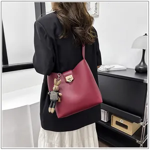 Détail du sac seau bordeaux en cuir mat avec charm lapin mignon et fermoir doré chic