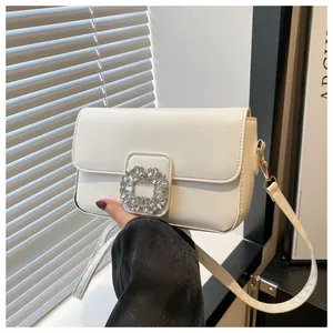 Detailed view of the sparkling crystal buckle on the white leather square shoulder bag