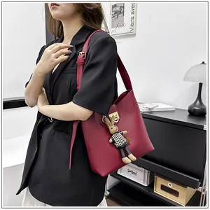 Détail d'un sac seau en cuir bordeaux avec boucle en métal doré et pendentif lapin