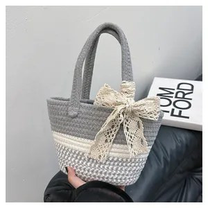 Detailed close-up of handmade woven tote bag featuring grey knit and white lace bow