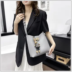 Détail d'un sac seau gris avec boucle dorée et un pendentif mignon en forme de lapin