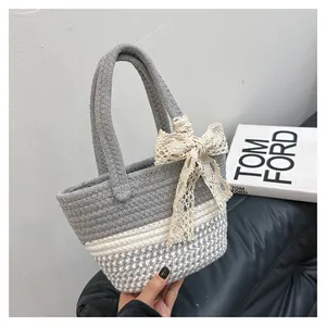 Detail of hand-woven cotton basket bag featuring a delicate lace bow and grey-white contrast
