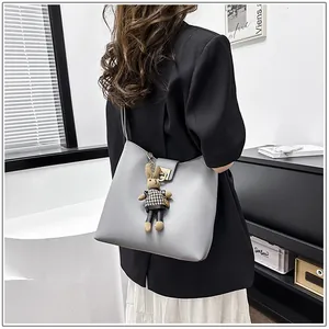 Détail du sac seau en cuir gris avec un pendentif lapin et un fermoir en métal doré