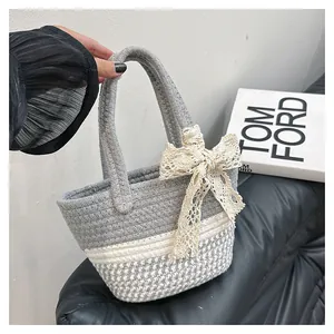 Detail of woven cotton tote bag featuring lace bow and grey houndstooth pattern