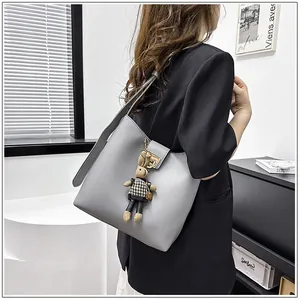Détail d'un sac seau gris avec un fermoir en métal et un porte-clé lapin trop mignon