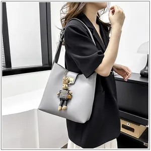 Sac seau en cuir gris avec bandoulière réglable et pendentif lapin en peluche sur le mannequin