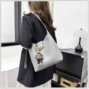 Détail d'un sac seau gris avec boucle dorée et charmant lapin en peluche stylé
