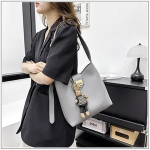 Détail du sac seau gris clair avec fermoir en métal et pendentif lapin sur un mannequin