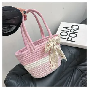 Detail of pink and white striped woven tote bag with cream lace bow for summer beach style