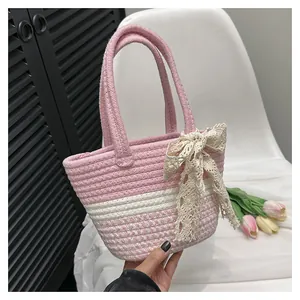 Close-up of pink woven basket bag featuring a delicate lace bow and cotton rope texture