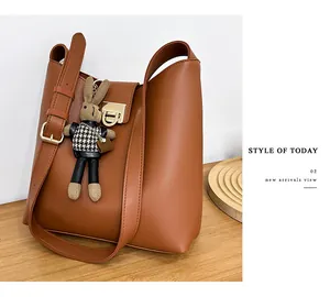 Détail d'un sac seau en cuir marron avec fermoir métallique et breloque lapin mignonne
