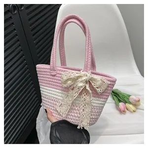 Close-up of pink and white woven cotton handbag with a large cream lace bow accent