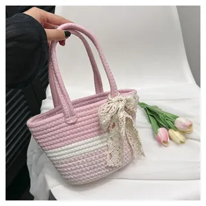 Detail of pink and white woven tote bag with beige lace bow and dual handles