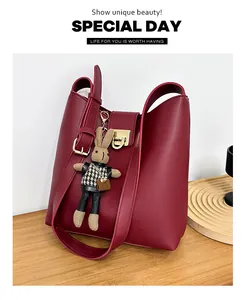 Vue détaillée du sac seau bordeaux avec fermoir doré et pendentif lapin en tricot