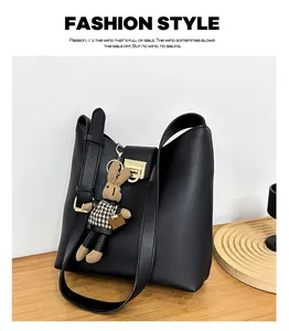 Détail d'un sac seau noir en cuir avec boucle dorée et charmant lapin en peluche marron
