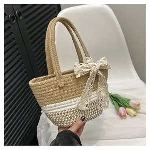 Detail of hand-woven straw bag featuring a white lace bow and bicolor mesh pattern