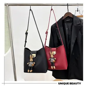 Détail de sacs seaux en cuir mat avec boucle métallique et breloque lapin en pied-de-poule