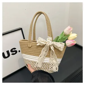 Detailed close-up of woven tote bag featuring white lace bow and textured straw pattern