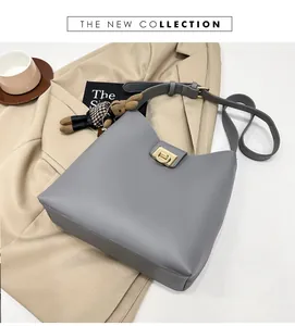 Détail du sac seau gris avec boucle dorée et charm peluche lapin à carreaux élégant