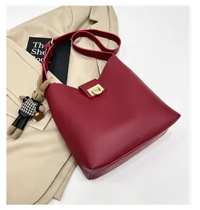 Détail du sac seau en cuir rouge foncé avec boucle dorée et breloque lapin en peluche