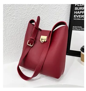 Détail du sac seau bordeaux en cuir texturé avec boucle métallique en forme de D dorée