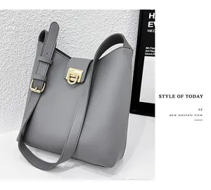 Détail du sac seau en cuir gris montrant la boucle carrée dorée et les coutures de précision