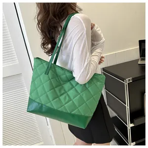 Green quilted tote bag with diamond pattern shown on shoulder in office setting