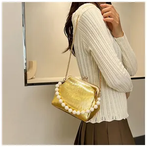Detailed view of a gold pleated clutch bag featuring oversized pearl handle and chain strap