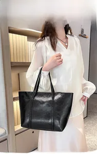 Model showcase of a large black faux leather tote bag for stylish office commuting