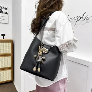 Sac seau noir minimaliste avec boucle dorée et pendentif lapin mignon porté par un mannequin