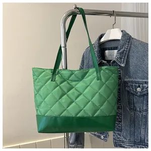 Detail of green quilted tote bag showing shiny nylon texture and leather bottom stitching