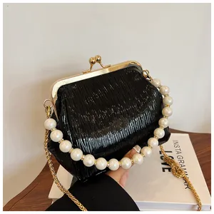 Detailed shot of black pleated shell bag with gold clasp and elegant pearl handle