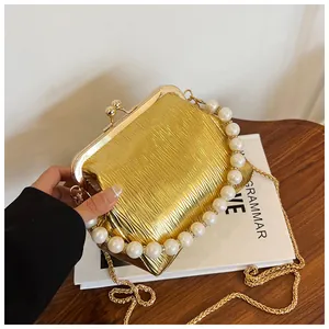 Close-up of golden pleated evening clutch bag with pearl handle and metal chain strap