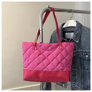 Detail of rose pink quilted tote bag hanging on a rack with denim jacket background