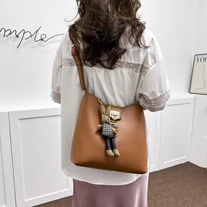 Sac seau en cuir marron avec fermoir métallique et breloque lapin, style épuré