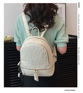 Detail of a beige PU leather backpack with embossed letters and a decorative pompom pendant