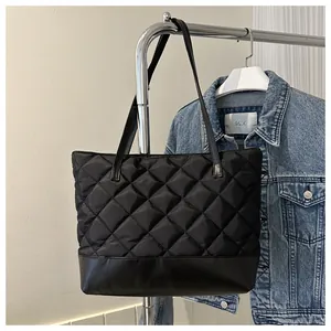 Close-up of black quilted nylon tote bag with leather base and sturdy shoulder strap
