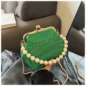 Close-up of green pleated shell bag with pearl handle and golden chain strap detail