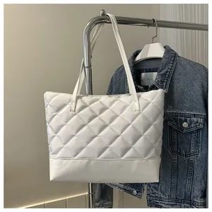 Detailed view of white quilted tote bag with diamond pattern and long shoulder straps