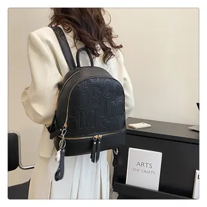 Close-up of black lychee grain leather backpack featuring luxury embossed letters and gold zipper