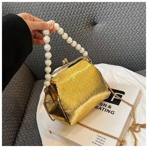 Detail of golden pleated shell bag with large pearl handle and vintage metal clasp