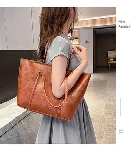 Detail view of a large brown vintage tote bag with long shoulder straps on a model