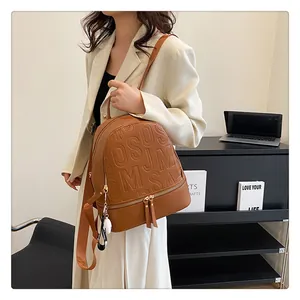 Detail of brown leather backpack with embossed letters and metal zipper close-up view