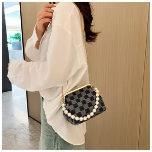 Detail of checkered shell bag featuring oversized pearl handle and gold chain strap