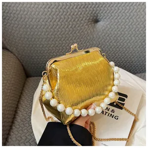 Detail of gold pleated shell bag with pearl handle and metal kiss-lock closure