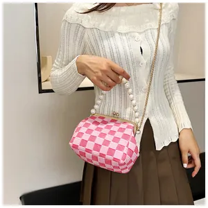 Detail of pink checkerboard handbag with pearl handle and golden clasp closure