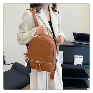Brown leather backpack with embossed letters and white smiley pendant in office scene