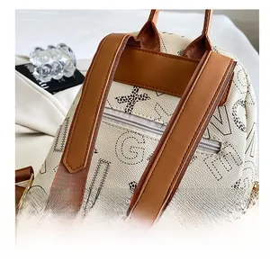 Detail of fashion backpack with letter prints, brown straps, and back zipper pocket